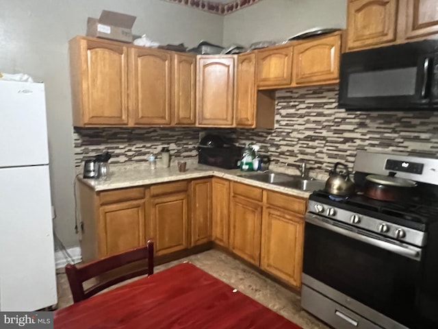 kitchen with tasteful backsplash, sink, white fridge, and stainless steel stove