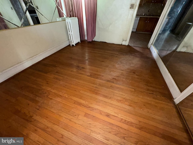 interior space featuring hardwood / wood-style floors, radiator heating unit, and sink