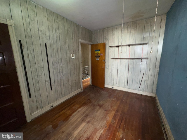 spare room with wood walls and dark wood-type flooring