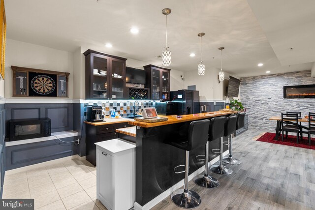 6616 Osborne Hill Dr, Upper Marlboro, MD 20772 - bar with black appliances, a stone fireplace, pendant lighting, wainscoting, and recessed lighting