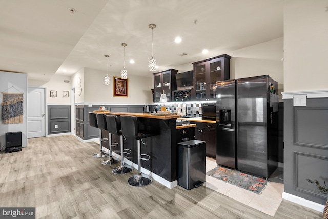 6616 Osborne Hill Dr, Upper Marlboro, MD 20772 - kitchen with black fridge with ice dispenser, a center island, light countertops, glass insert cabinets, and a breakfast bar area