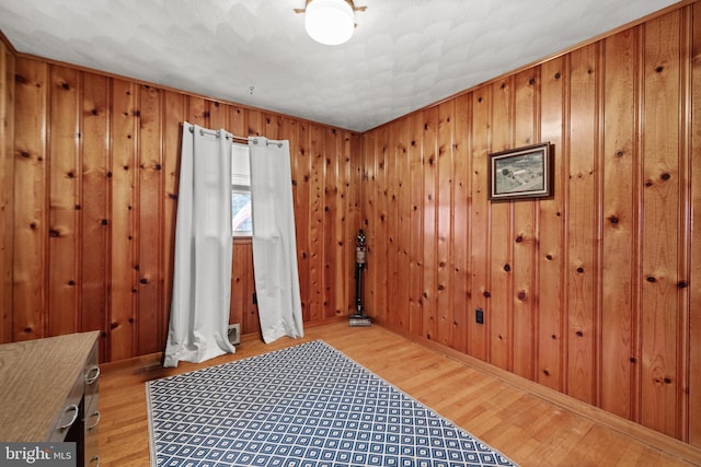 bedroom featuring light hardwood / wood-style floors and wooden walls