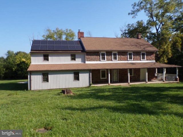 back of property featuring a yard and solar panels