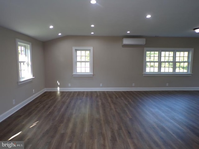 unfurnished room featuring a wall mounted air conditioner, lofted ceiling, and dark wood-type flooring