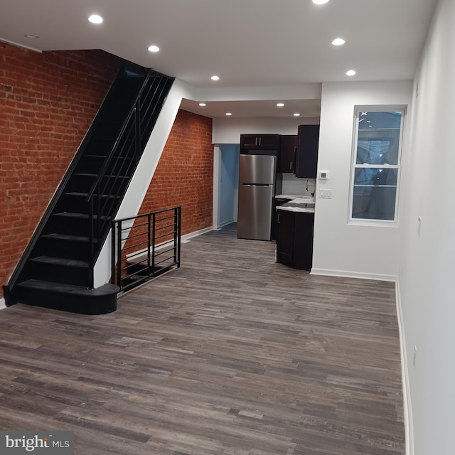 kitchen featuring stainless steel fridge, sink, brick wall, and wood-type flooring