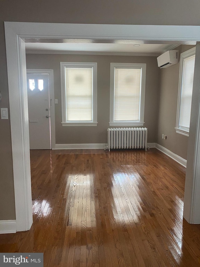 entrance foyer featuring hardwood / wood-style flooring, an AC wall unit, and radiator