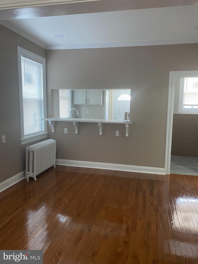 spare room with radiator, crown molding, and dark hardwood / wood-style floors