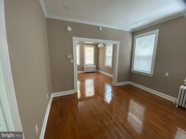 empty room with radiator heating unit, an AC wall unit, ornamental molding, and wood-type flooring