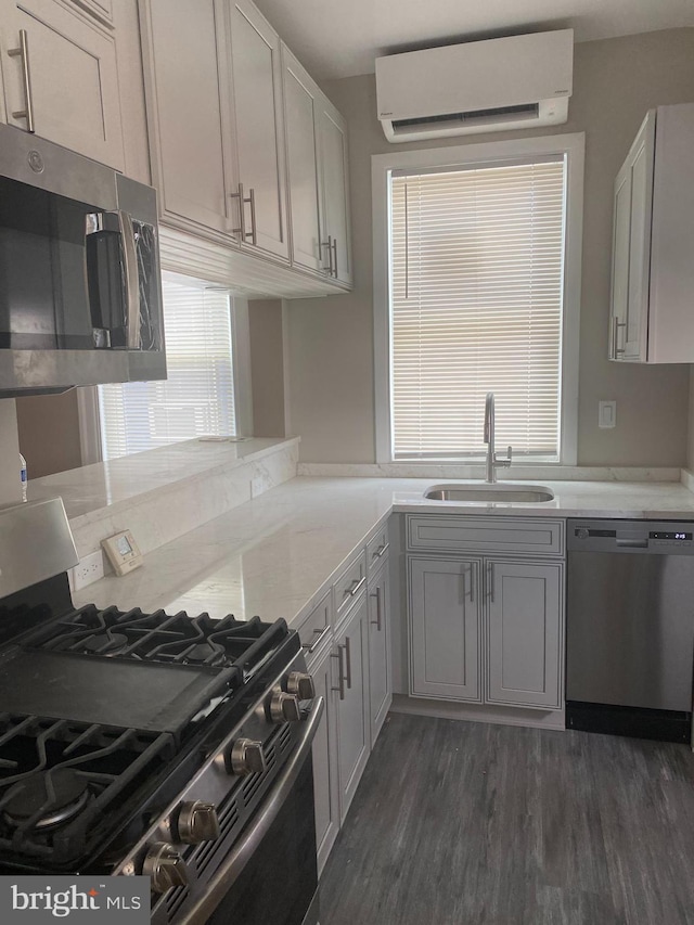 kitchen featuring appliances with stainless steel finishes, dark hardwood / wood-style flooring, a wall unit AC, and sink