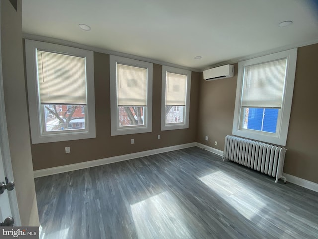 unfurnished room featuring an AC wall unit, dark hardwood / wood-style flooring, and radiator heating unit