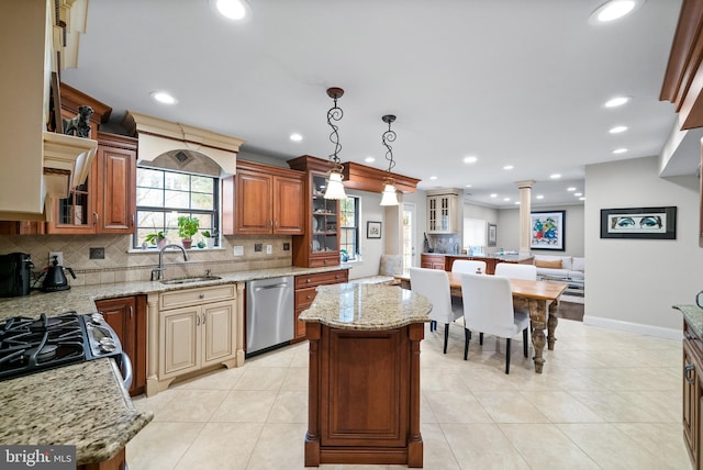 kitchen featuring sink, light stone countertops, decorative light fixtures, a kitchen island, and stainless steel appliances