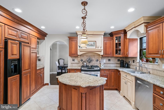 kitchen with light stone countertops, tasteful backsplash, stainless steel appliances, sink, and pendant lighting