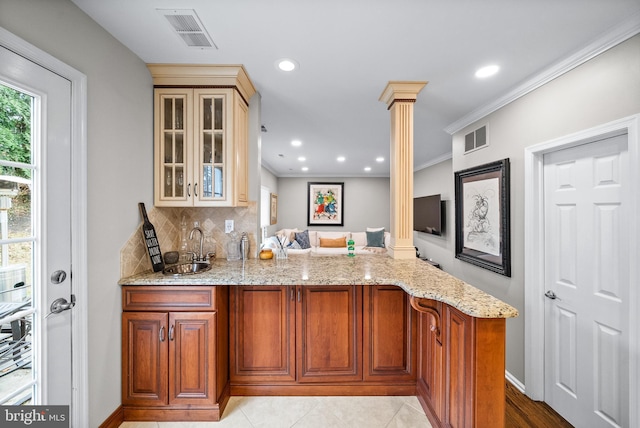 kitchen featuring crown molding, sink, light stone countertops, kitchen peninsula, and decorative columns