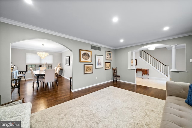 living room featuring crown molding, dark wood-type flooring, and an inviting chandelier