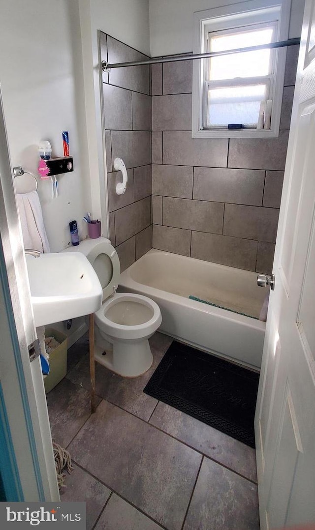 bathroom featuring tile patterned floors, tiled shower / bath combo, and toilet