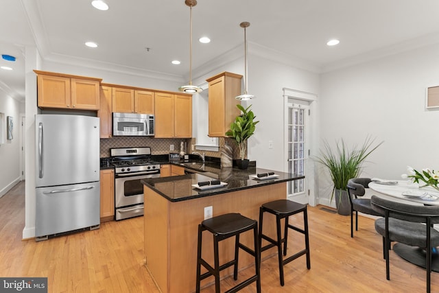 kitchen featuring sink, stainless steel appliances, light hardwood / wood-style flooring, kitchen peninsula, and pendant lighting