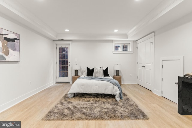 bedroom featuring light hardwood / wood-style floors, a raised ceiling, and ornamental molding