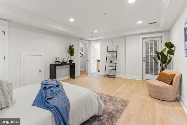 bedroom featuring access to exterior, wood-type flooring, and a tray ceiling