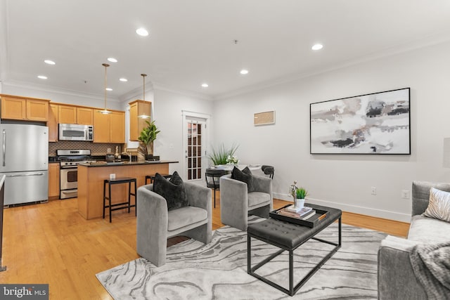 living room with sink, light hardwood / wood-style flooring, and ornamental molding