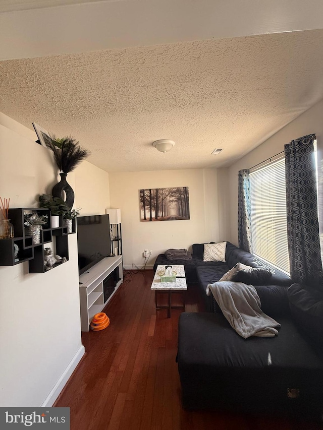 living room with a textured ceiling and dark wood-type flooring