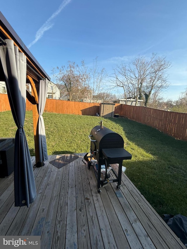 wooden deck featuring a grill and a lawn