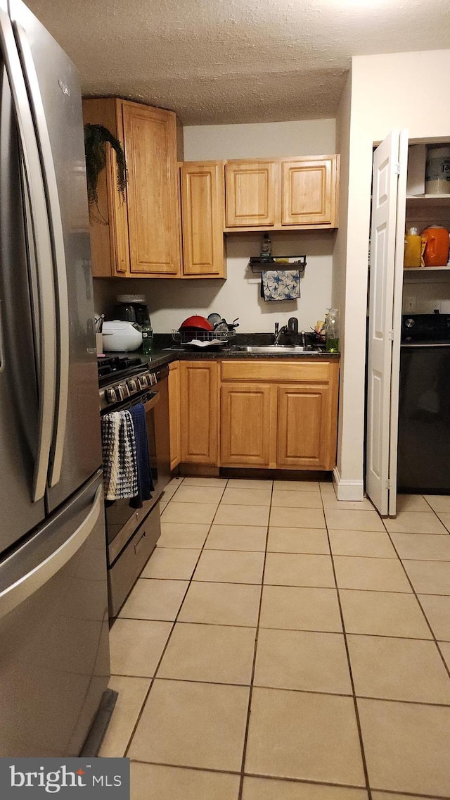 kitchen with light tile patterned floors, a textured ceiling, stainless steel appliances, and sink