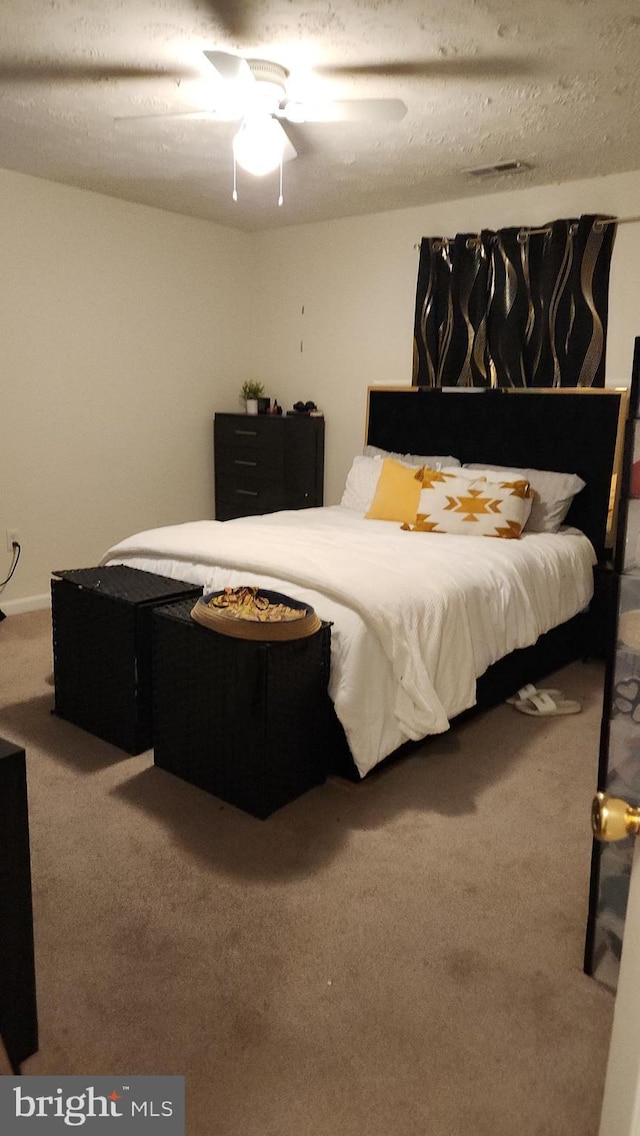 carpeted bedroom with ceiling fan and a textured ceiling