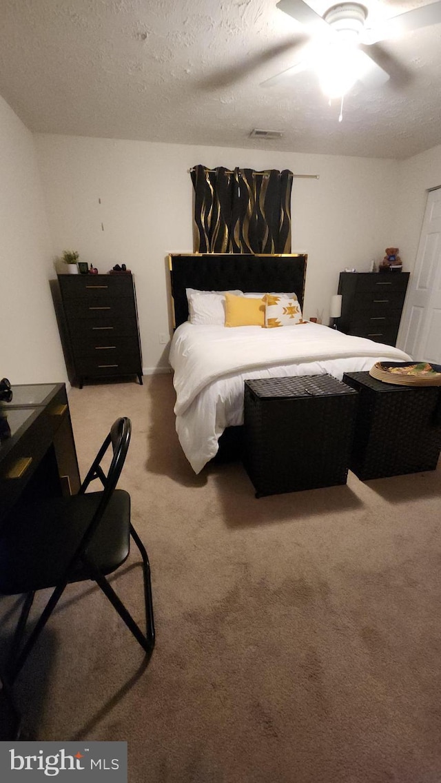 carpeted bedroom featuring ceiling fan and a textured ceiling