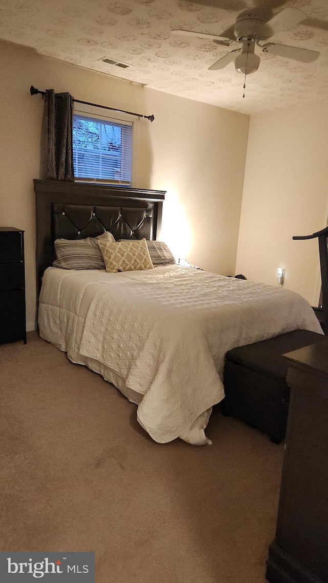 carpeted bedroom with ceiling fan and a textured ceiling