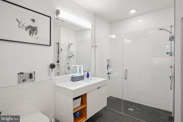 bathroom featuring vanity, a shower with door, tile patterned floors, toilet, and tile walls