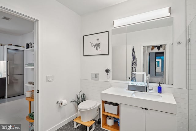 bathroom featuring vanity, tile walls, and toilet