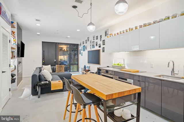 kitchen with white cabinetry, sink, hanging light fixtures, tasteful backsplash, and electric cooktop