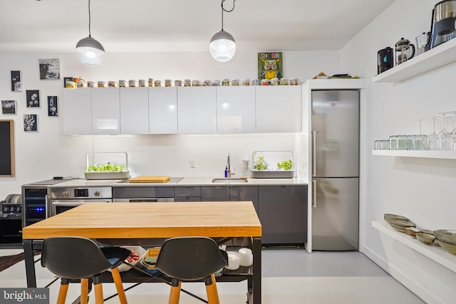 kitchen with stainless steel appliances, white cabinetry, hanging light fixtures, and sink