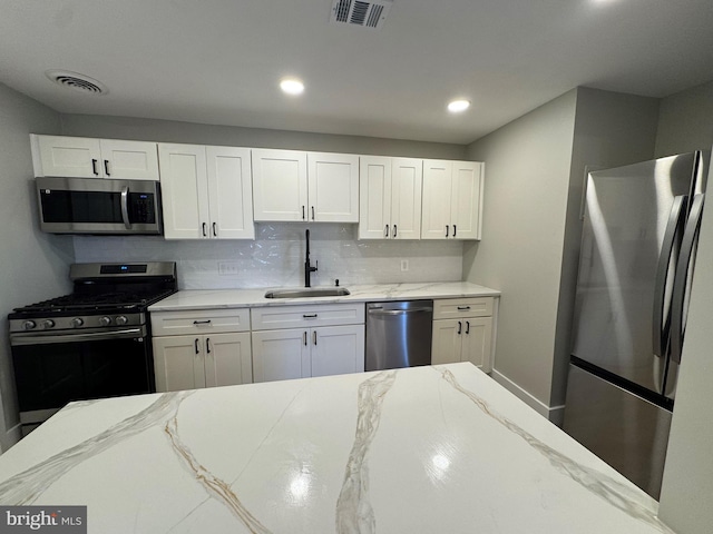 kitchen with tasteful backsplash, white cabinetry, sink, and stainless steel appliances