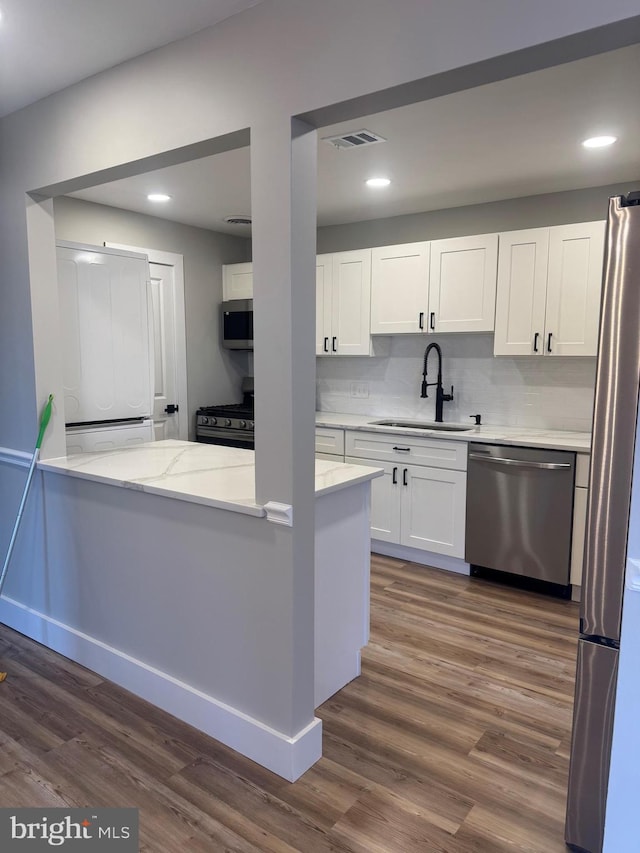 kitchen with dark wood-type flooring, white cabinets, sink, kitchen peninsula, and stainless steel appliances