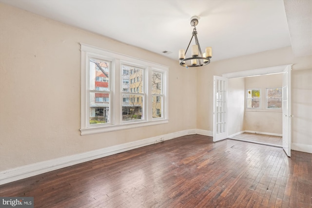 unfurnished dining area with french doors, dark hardwood / wood-style flooring, an inviting chandelier, and a healthy amount of sunlight