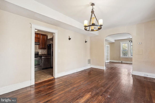 spare room featuring a notable chandelier and dark hardwood / wood-style floors