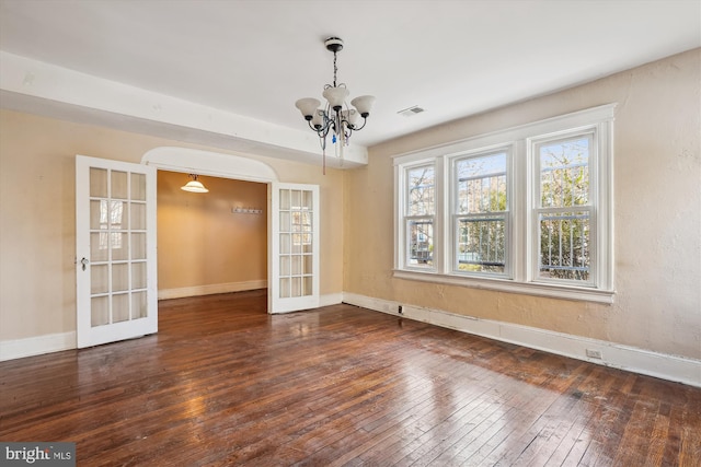 unfurnished room featuring an inviting chandelier, dark hardwood / wood-style flooring, and french doors