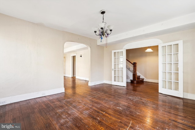 unfurnished room featuring french doors, dark wood-type flooring, and an inviting chandelier