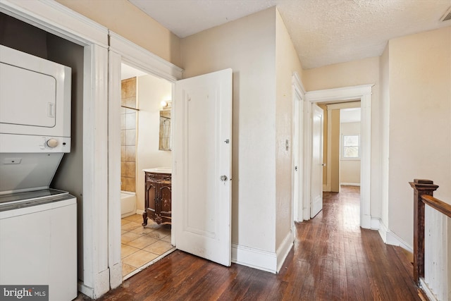 washroom featuring a textured ceiling, stacked washer / dryer, and dark wood-type flooring