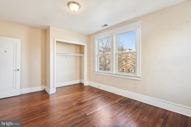 unfurnished bedroom with a closet and dark hardwood / wood-style floors