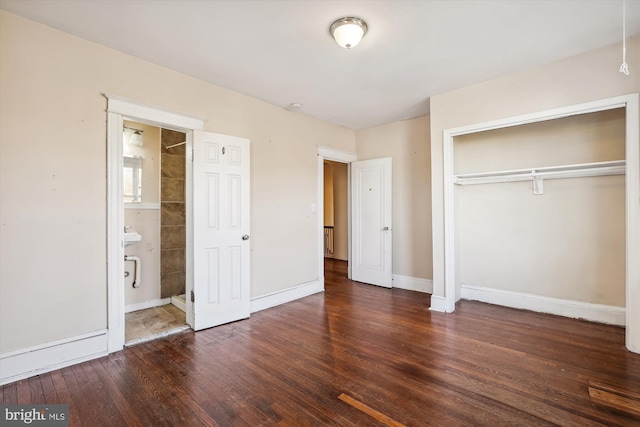 unfurnished bedroom with ensuite bath, dark wood-type flooring, and a closet