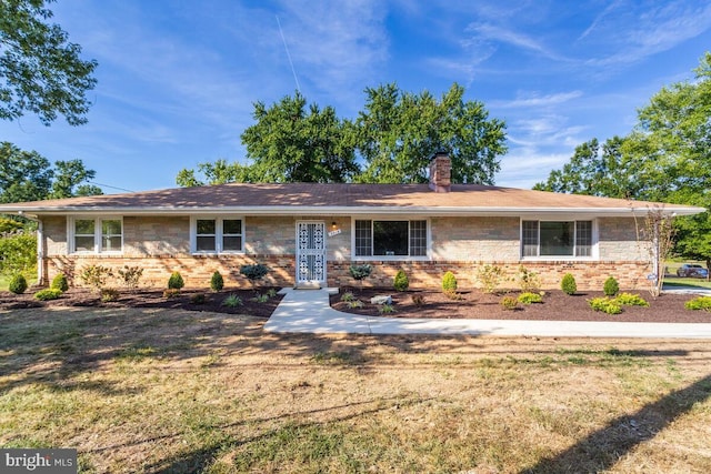 single story home with brick siding, a chimney, and a front yard