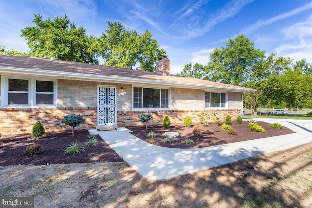 ranch-style house with a chimney and brick siding