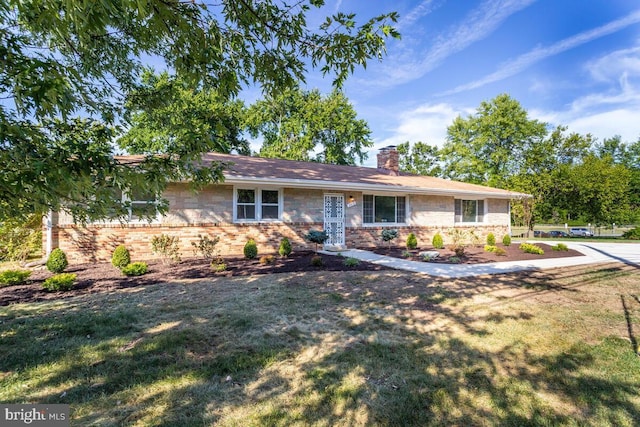 single story home featuring a front yard, brick siding, and a chimney