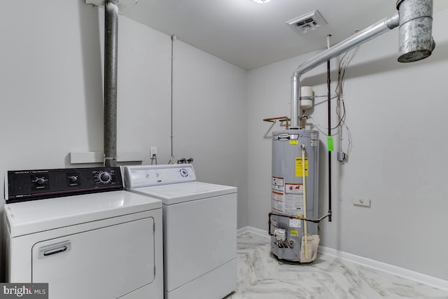 clothes washing area featuring gas water heater, visible vents, separate washer and dryer, laundry area, and baseboards