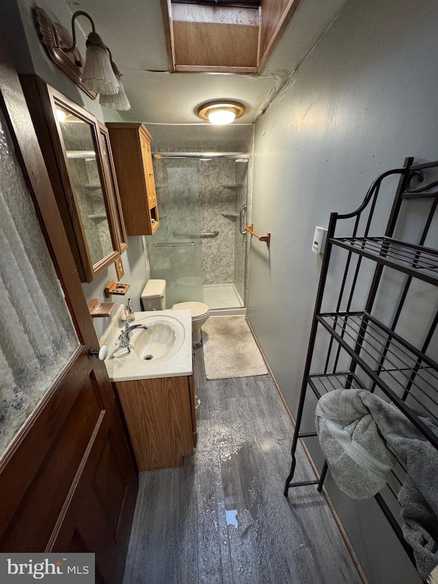 bathroom featuring vanity, toilet, wood-type flooring, and a shower with door