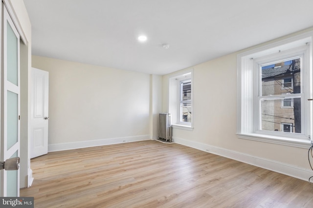 unfurnished room with light hardwood / wood-style floors and radiator