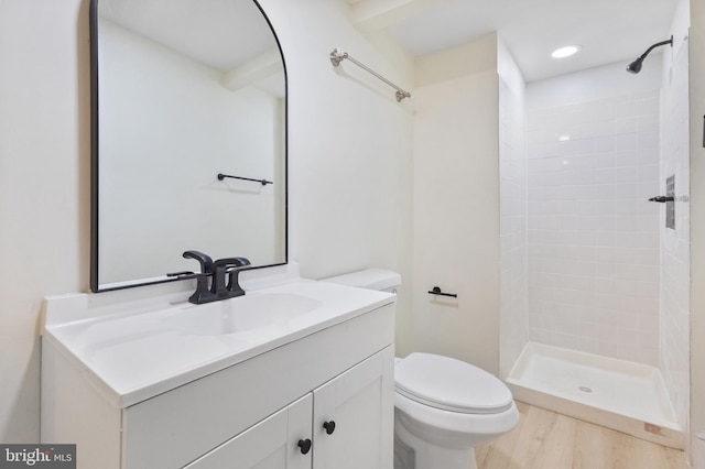 bathroom featuring hardwood / wood-style floors, vanity, a tile shower, and toilet