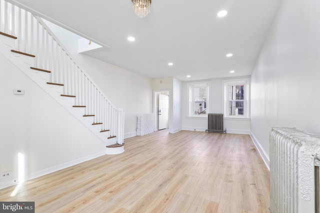 unfurnished living room with radiator, a chandelier, and light hardwood / wood-style floors